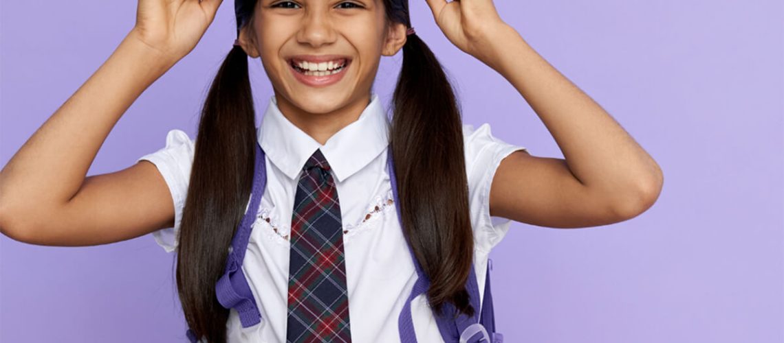 Child in school uniform with book on her head